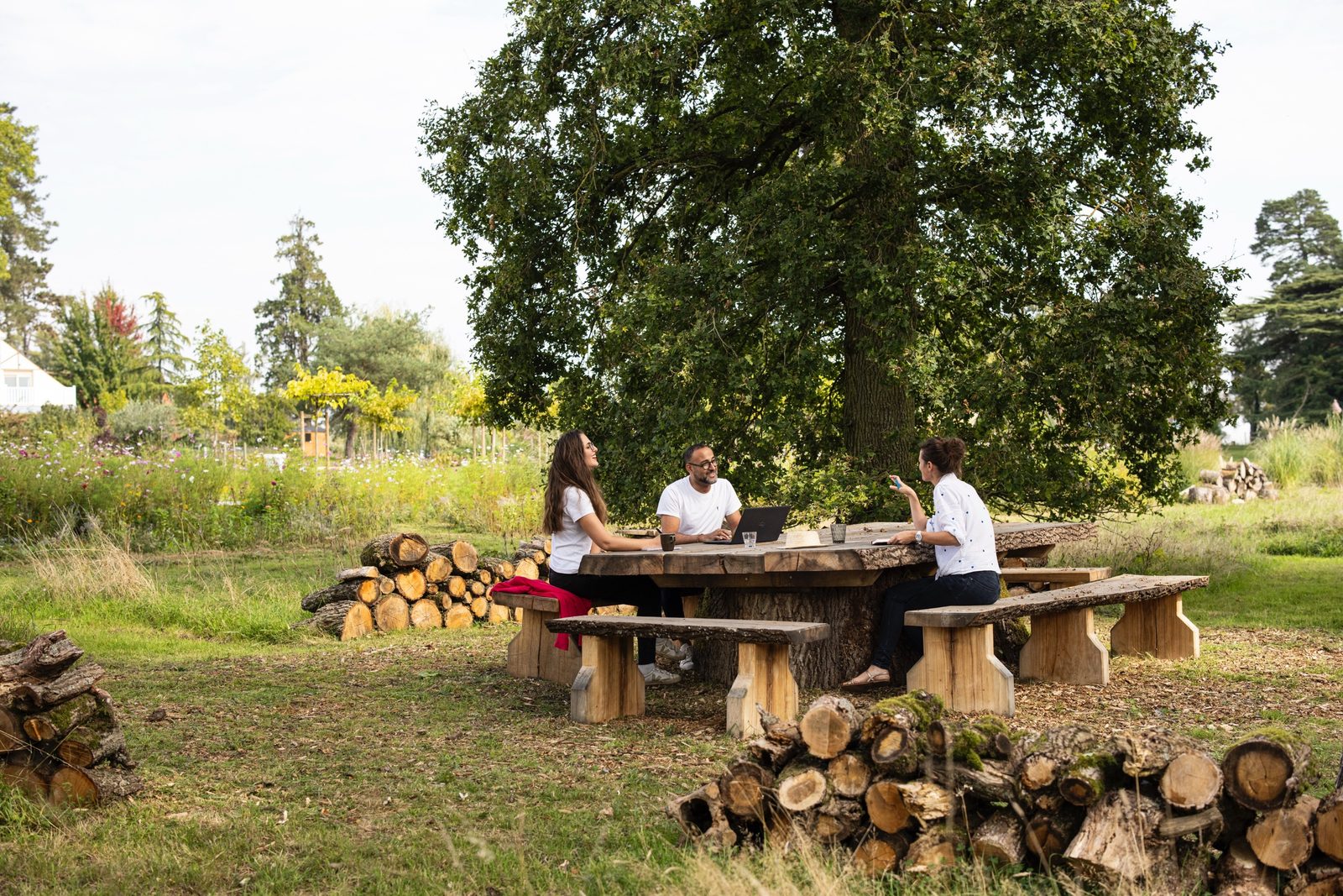 Participants travaillant à une table en bois sous un grand arbre